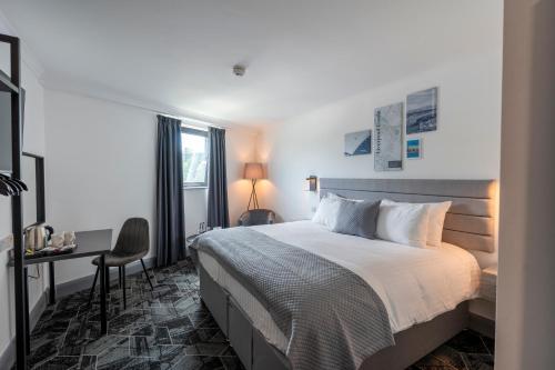 a bedroom with a bed and a desk and a window at The Bolton Stadium Hotel, a member of Radisson Individuals in Bolton