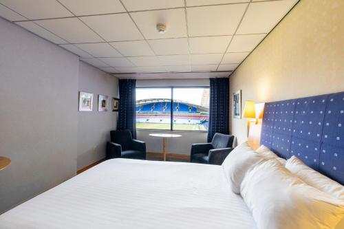 a hotel room with a bed and chairs and a window at The Bolton Stadium Hotel, a member of Radisson Individuals in Bolton