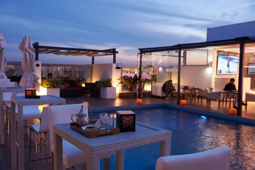 a patio with tables and chairs and a pool at Mövenpick Hotel Casablanca in Casablanca