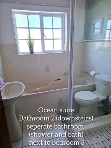a bathroom with a tub and a toilet and a sink at Mond Kleine Guest House in Kleinmond
