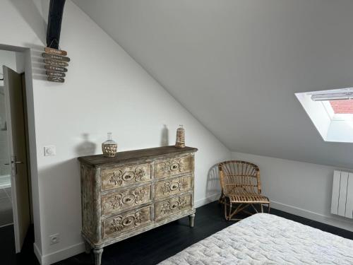 - une chambre mansardée avec une commode et un lit dans l'établissement Bohème chic, à Faremoutiers