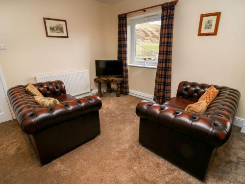 a living room with two leather couches and a television at Keartons - Buttertubs in Richmond