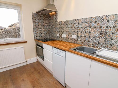 a kitchen with white cabinets and a sink and a window at Keartons - Buttertubs in Richmond