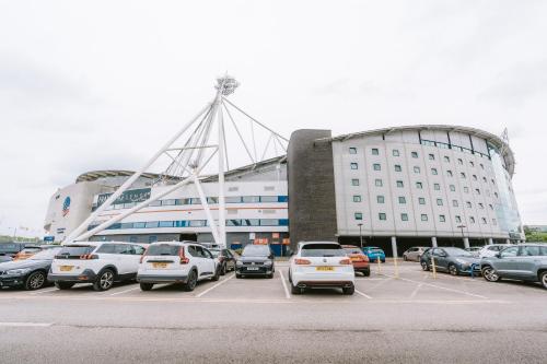 a parking lot with cars parked in front of a building at The Bolton Stadium Hotel, a member of Radisson Individuals in Bolton