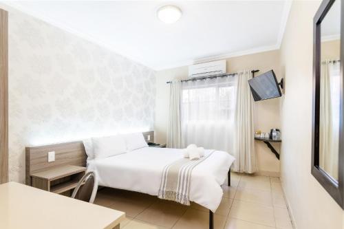 a bedroom with a white bed and a window at Auas City Hotel in Windhoek