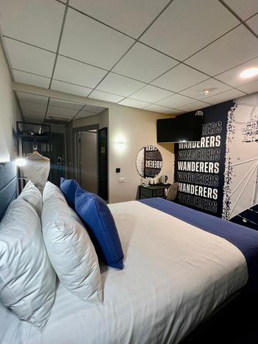 a large white bed with blue pillows in a room at The Bolton Stadium Hotel, a member of Radisson Individuals in Bolton