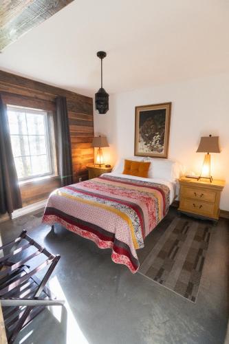a bedroom with a bed and two tables and two lamps at La Ruelle Hébergement in Saint-Siméon