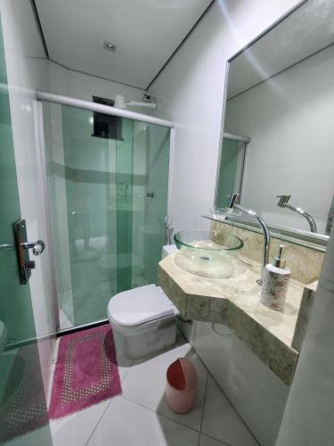 a bathroom with a glass sink and a toilet at Apartamentos - Repouso do Guerreiro in Itabuna