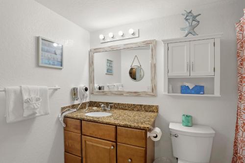 a bathroom with a sink and a toilet and a mirror at South Beach Condo Hotel by Travel Resort Services, Inc. in St. Pete Beach