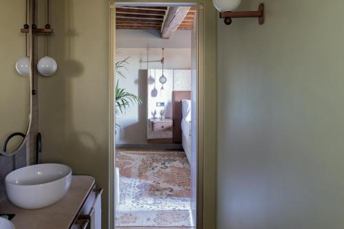 a bathroom with a door open to a bathroom with a sink at Borgo Dei Conti Resort Relais & Chateaux in Monte Petriolo