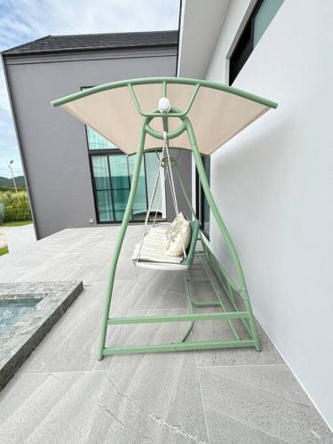 a swing sitting on the side of a house at Gaia Pool Villa Khao Yai in Ban Bung Toei
