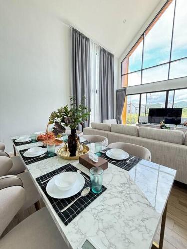 a living room with a table with plates on it at Gaia Pool Villa Khao Yai in Ban Bung Toei