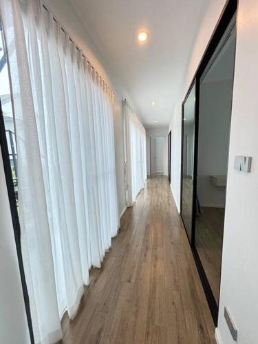 an empty hallway with white curtains and wooden floors at Gaia Pool Villa Khao Yai in Ban Bung Toei
