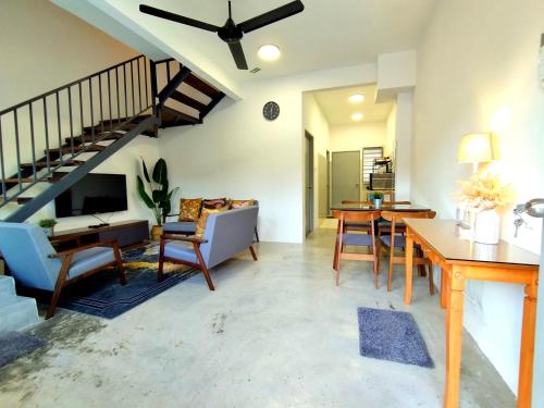 a living room with a staircase and a table and chairs at Soffea D'Homestay Pagoh - WiFi , NetFlix in Pagoh