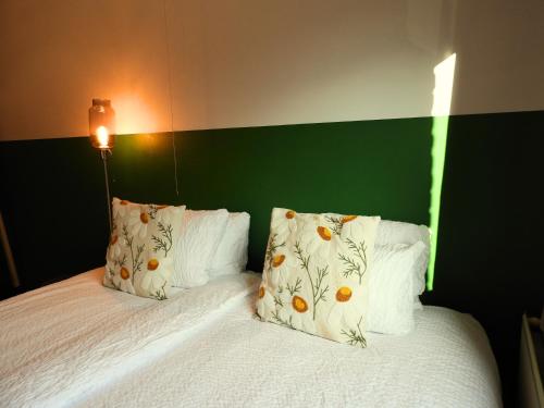 a bed with white pillows and a green headboard at Guesthouse De Wissen in Dilsen-Stokkem