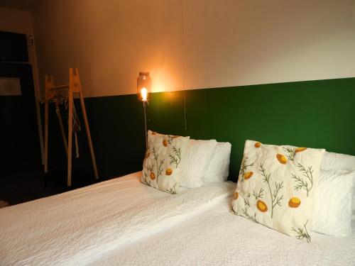a bed with two pillows and a green headboard at Guesthouse De Wissen in Dilsen-Stokkem