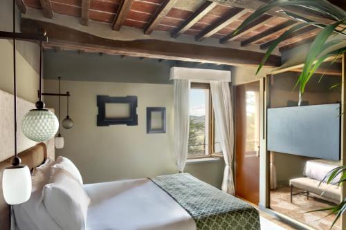 a bedroom with a bed and a large window at Borgo Dei Conti Resort Relais & Chateaux in Monte Petriolo