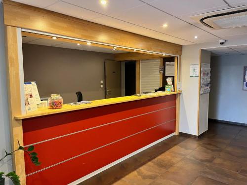 a restaurant with a red and yellow counter at Brit Hotel Confort Montauban in Montauban