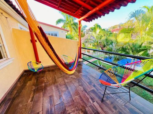 a porch with two chairs and a hammock on a balcony at Casa a 7 min de playa in Ixtapa