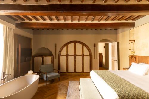 a bedroom with a tub and a bed and a bath tub at Borgo Dei Conti Resort Relais & Chateaux in Monte Petriolo