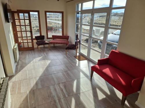 a living room with a red couch and chairs and windows at Hosteria Lago Sur in El Calafate