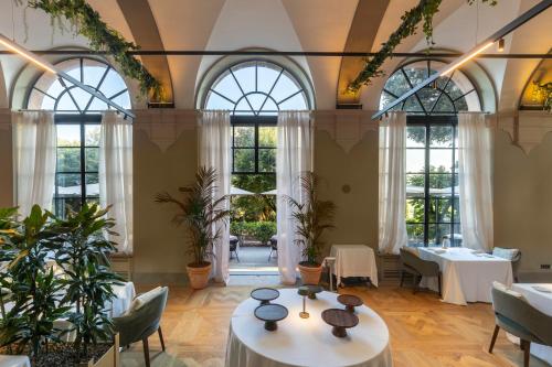 a restaurant with tables and chairs and windows at Borgo Dei Conti Resort Relais & Chateaux in Monte Petriolo