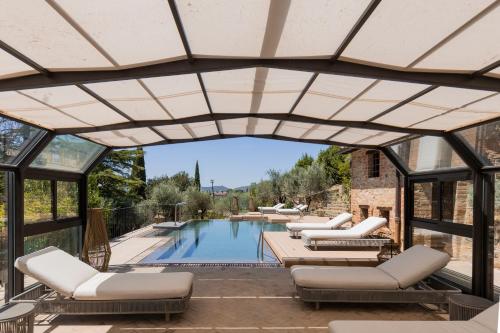 a patio with chairs and a swimming pool with a retractable roof at Borgo Dei Conti Resort Relais & Chateaux in Monte Petriolo