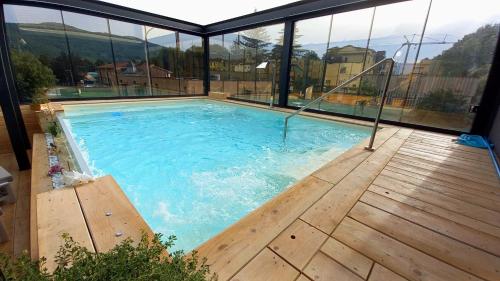 a large swimming pool with a wooden deck and windows at Hotel Giardino in Bibbiena