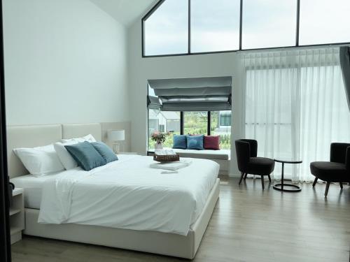 a white bedroom with a bed and a couch at Gaia Pool Villa Khao Yai in Ban Bung Toei