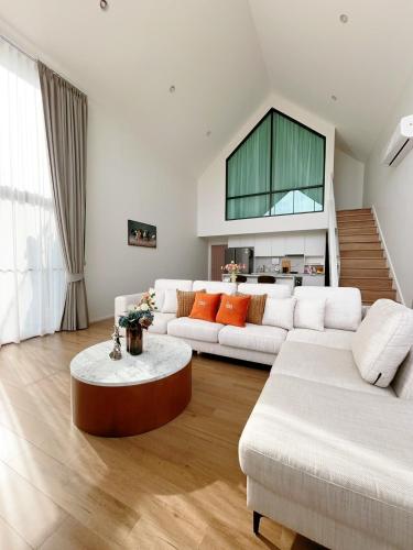 a living room with two white couches and a table at Gaia Pool Villa Khao Yai in Ban Bung Toei
