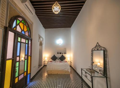 a bedroom with a bed and a stained glass window at Riad Nashira in Fès