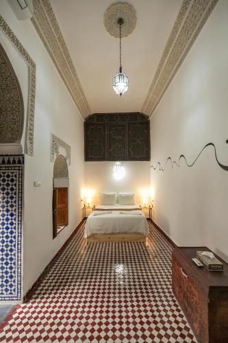 a bedroom with a bed and a red and white floor at Riad Nashira in Fès