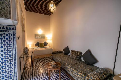 a room with two beds and a table in it at Riad Nashira in Fès