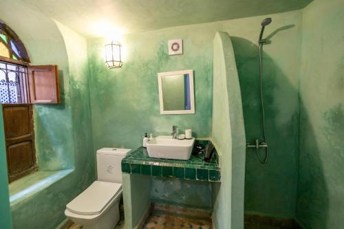 a green bathroom with a sink and a toilet at Riad Nashira in Fès