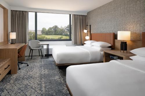 a hotel room with two beds and a desk at Sheraton Westport Plaza in Maryland Heights