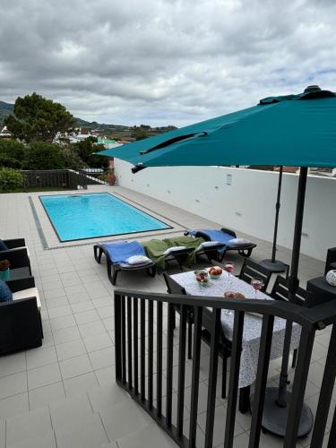 a balcony with a table and an umbrella and a swimming pool at Casa da Lara in Lagoa