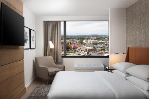 a hotel room with a bed and a large window at Sheraton Westport Plaza in Maryland Heights