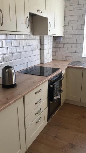 a kitchen with white cabinets and a stove top oven at Maurice House 3 bedroom self catering townhouse in Bangor