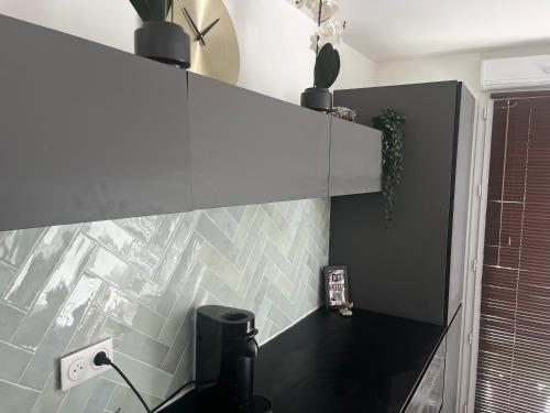 La salle de bains est pourvue d'un comptoir noir et d'un mur en carrelage. dans l'établissement Stade Nautique Vaires sur Marne, à Vaires-sur-Marne