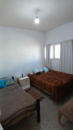 a bedroom with two beds and a couch and a window at Casa Oliva in Tinogasta