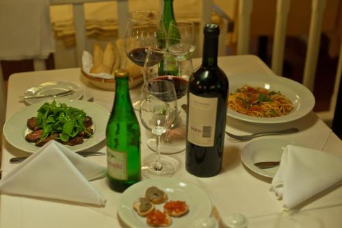 a table with two bottles of wine and plates of food at Hotel Posada La Sorgente in Puerto Iguazú