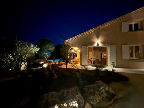 une maison la nuit avec des lumières devant elle dans l'établissement Maison pour 12p, piscine à débordement chauffée d'avril à octobre inclus, à Ruoms