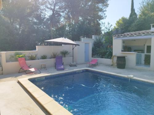 une piscine avec deux chaises et un parasol dans l'établissement Villa piscine et climatisation, à Sauveterre