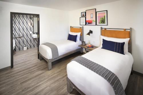 a hotel room with two beds and a mirror at voco The Tuxon by IHG in Tucson