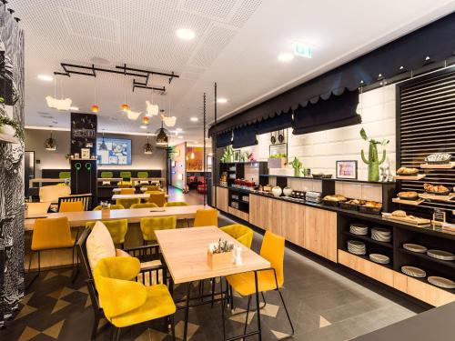 a restaurant with yellow chairs and a table and counters at Holiday Inn - the niu, Cobbles Essen by IHG in Essen