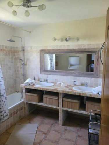 une salle de bain avec deux lavabos, une baignoire et un miroir dans l'établissement Villa provençale à Arles avec piscine privée et vue jardin., à Arles