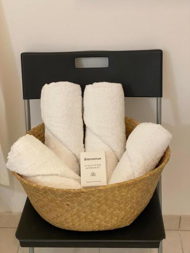 un panier rempli de serviettes blanches sur une étagère dans l'établissement Spacieux appart terrasse métro hôpital 4pers wifi, à Villejuif