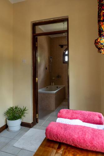 a bathroom with a tub and a pink ottoman at Hansat Homestay Residence in Arusha