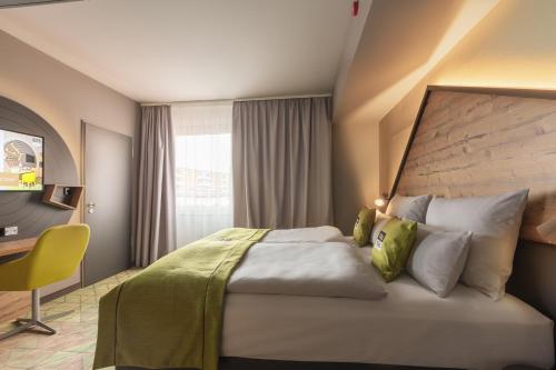 a bedroom with a large bed with a yellow chair at Holiday Inn - the niu, Mill Cologne Mülheim by IHG in Cologne