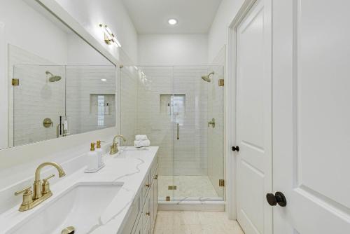 a white bathroom with two sinks and a shower at Salt & Stone Villas in Galveston